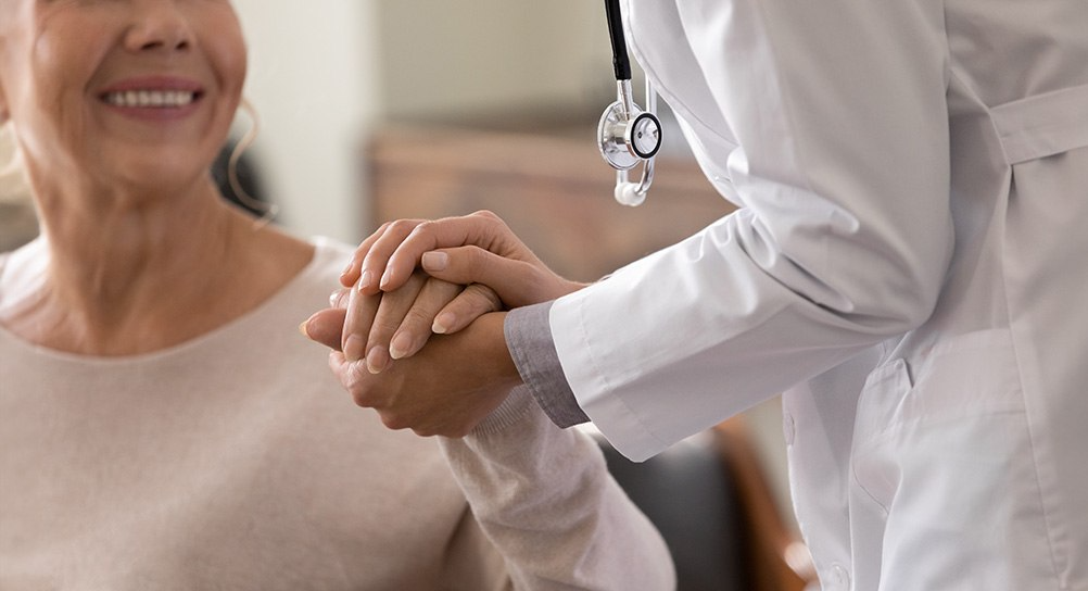 Doctor holding smiling elderly woman's hand 