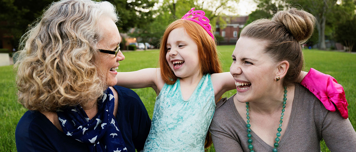 A little girl sits between her grandmother and mother