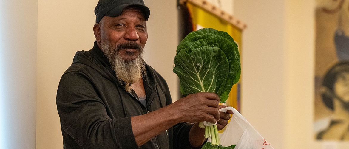 Man holds up a bunch of collard greens