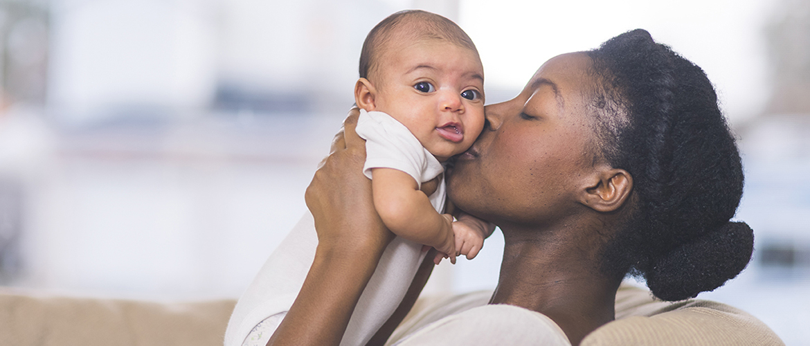 New mother hold up infant to her face and kisses its cheek