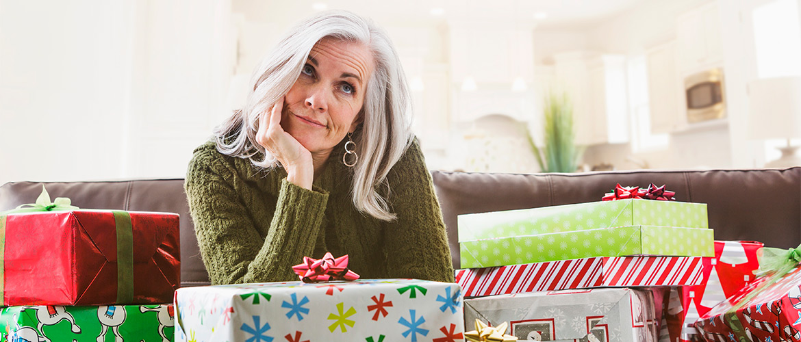 Woman props up her head with her arm on a Christmas-wrapped gift box