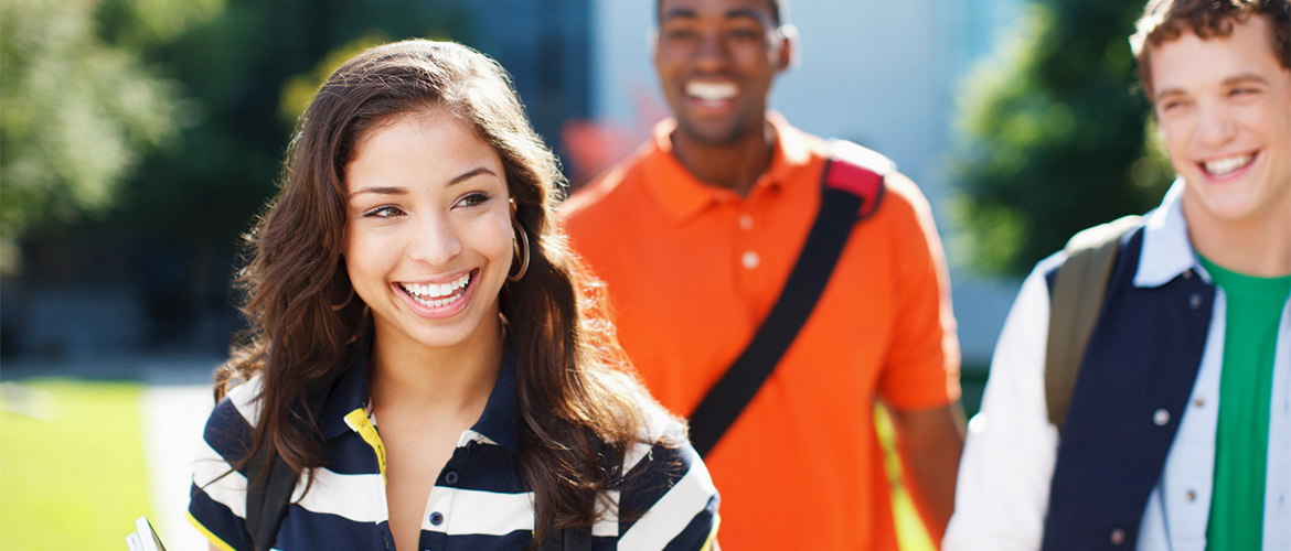 A woman smiles as she walks ahead of two smiling men