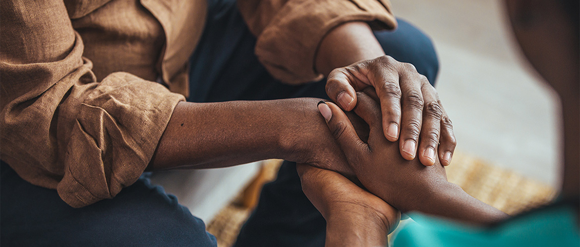 Two people sitting and one holding the hands of the other