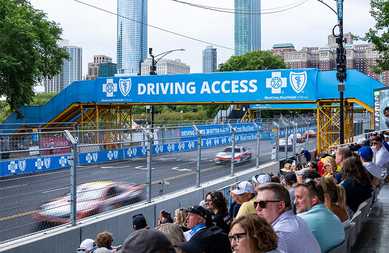 race cars drive on city track as spectators look on