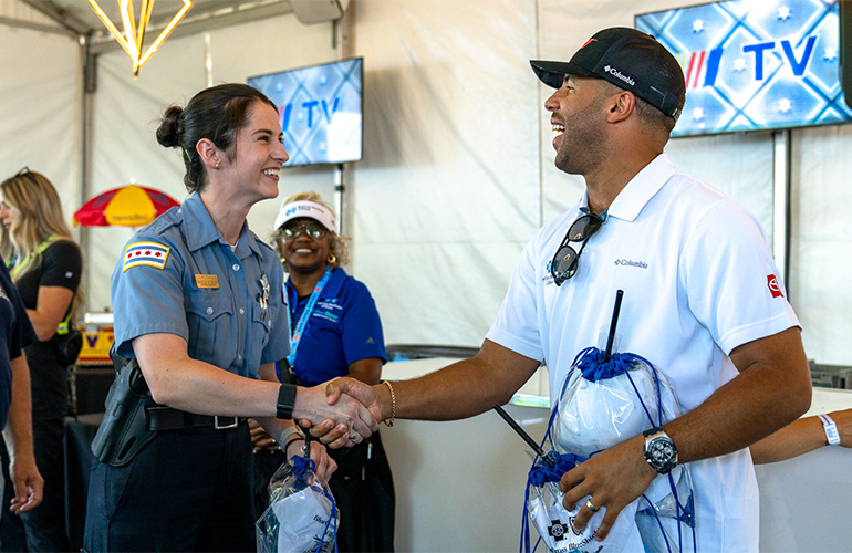 female police officer in uniform shakes hands with man in white shirt