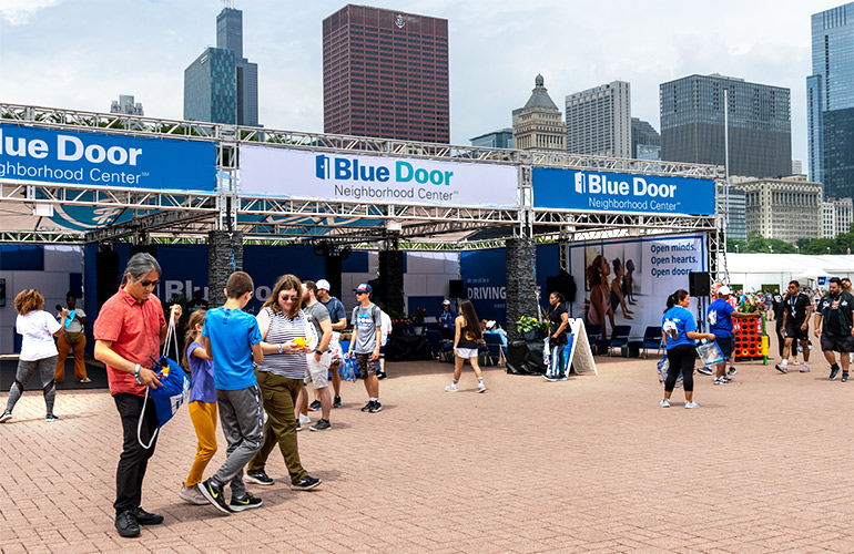 Crowd walks in city near outdoor neighborhood center during event