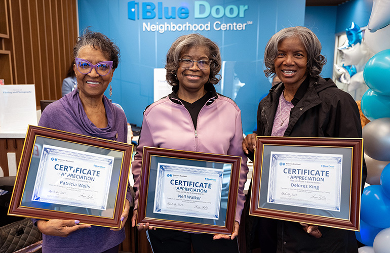 Women pose for camera holding certificates